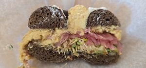 Toasted Rye (was actually pumpernickle) Bagel with hummus, Sprouts, Pickled Red Onion had to be remade because it got cut with a knife that left a cream cheesesmear on vegan order at Bagel Cafe in Camden