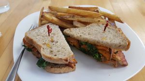 BBQ tofu sandwich with sweet potato medallions, kale and mayo on sourdough bread, with a side of fries.  at Grow Your Roots Cafe in Ottawa