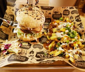 Reggae burger (black bean patty, vegan cheese and tofu bacon, lettuce and tomato, jackfruit, coleslaw, red onion, bermuda sauce, and peach chutney), served with Hawaiian poutine. at Boon Burger Cafe in Guelph