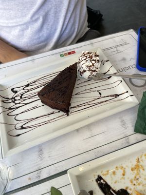 Torta caprese vegana servita con panna montana vegetale (with no cherry jam)  at Origano Campo de' Fiori in Rome