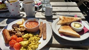 Tempeh bacon, mini hash browns, wilted spinach, scrambled tofu, black pudding (!), baked beans, sausage, mushrooms, tomatoes, toast and coffee with oat milk!!!! at Plant by Kat's Kitchen in Keswick