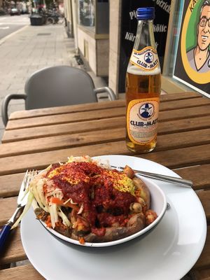 Delicious kumpir with couscous, mushrooms, chickpeas, shredded cabbage, spicy tomato sauce, vegan butter, and a ginger-turmeric sauce on top   at KartoffelKonig in Munich