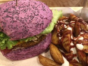 Flower burger on a pink bun with patatas bravas. at Flower Burger in Rome