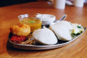 Idli set with three idlis (fermented black lentil rice cakes). sambar (lentil stew), coconut chutney, vada (savory fried donuts) with chili sauce, shredded coconuts and zucchini.  at Yama-Shoku-On - Plant Lab in Kyoto