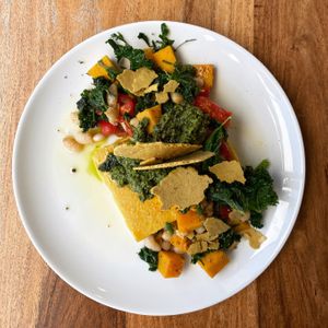 Baked polenta with white beans, pumpkin, pesto, little tomatoes, lemon infused extra virgin olive oil, cashew 'parmesan'. at The Little Shop of Plenty in Maylands