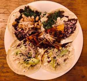 Un plato de tacos: barbacoa de berenjena (pulled eggplant), papas con chorizo, asada de soya (roasted soy), birria de hongos (mushroom) at La Flaca - Americana in Guadalajara