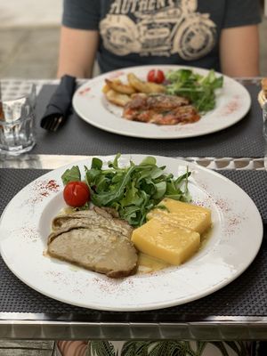 Roast of seitan with polenta and salad & eggplant Parmesan with salad and baked potatoes in the back. at La Tecia Vegana in Venice