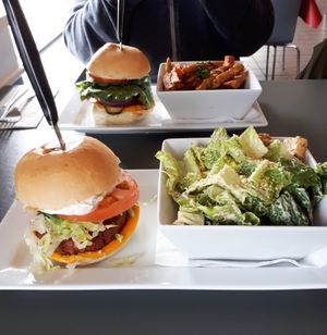 Mediterranean Burger (with cheese, feta, onion, lettuce, tomato, and tzatziki) served with Caesar salad. The Beyond Burger (with cheese, basil pesto, pickles, onion, lettuce, tomato, and mayo) served with poutine. at The Lemon Tree in St Catharines
