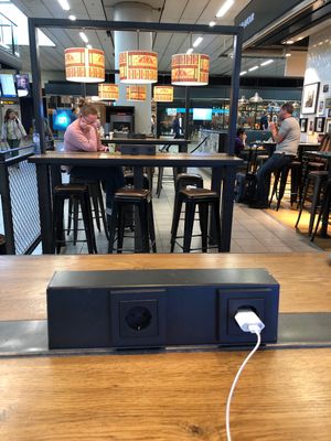 Charging sockets on the tables in the back at AMS - LEON in Schiphol