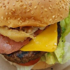 Fuzzlord's Happy Holiday Burger (All Vegan Ingredients) - vegan patty with  bacon style rashers, cheddar style cheese, onion rings, avocado tomato & lettuce & BBQ sauce  at Sicily to Seattle in Newport