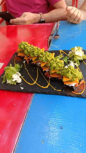 Focaccia negra con calabaza asada, "salmón", tomate seco, queso crema y hummus de espinacas at Sanissimo - Principe Pio in Madrid