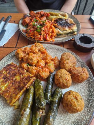 Front plate has falafel, stuffed vine leaves, courgette fritter and some bulgar meatballs, back plate has borek, bulgar salad, Seitan and cabbage rolls at Vegan Istanbul in Istanbul