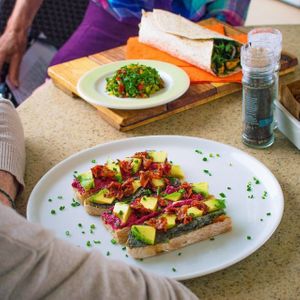 Top: Our best-selling Stir Fried Kale Wrap with Indonesian herbs, caramelised onions, roasted almond and smokey tofu. Served with a side salad.
Bottom: Our Pink & Black Hummus breakfast toast with Avo & Sundried Tomatoes on a bed of rocket at Namaste Lifestyle Cafe in Western Cape