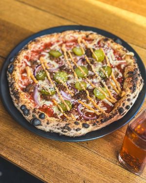 Cheeseburger pizza, topped with pickles, onion, mozzarella and crumbled grilled burger pieces, topped with housemade special burger sauce at Red Sparrow Pizza in Collingwood