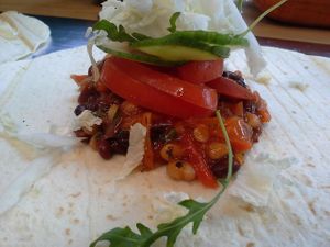Vegan burrito with red and white beans in tomato souce ,onion,carrot,paper, served with fresh tomato, cucumber,salat leaves and wrap in tortilia at Vegan.FTK in Moscow