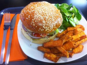 Veggie Burger with salad, tomatoes, dill pickles, red onions, grilled mushrooms and homemade BBQ sauce. Served with sweet potatoes fries and a small salad with special dressing (Tamari sauce and Maple sirup). 10 euros with an organic soda ! at Chic Planete in Avignon