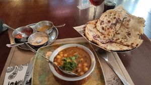 Plato de garbanzos y patatas cocidas y salsa de curry cilantro. Para acompañar, pan de/con cebolla. (No recuerdo el nombre de los platos tal y como aparecen en la carta). at Taj Mahal in Sevilla