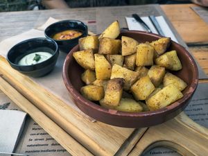 Patatas Bombay especiadas al horno con salsa picante, zanahoria, cacahuete y ají y alioli vegano at El Manglar in Oviedo