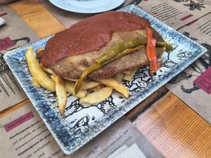 Cachopo tradicional con patatas fritas y tiras de pimiento asado at El Manglar in Oviedo