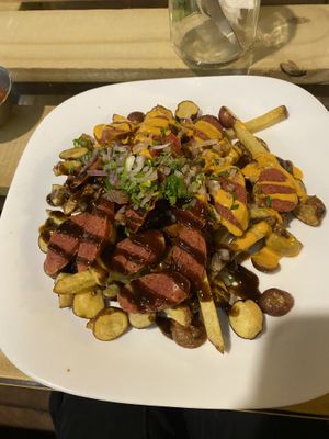 Salchipapas - chips with fake meat, little potatoes, vegan cheese sauce, bbq sauce and other toppings   at Go Green in La Paz