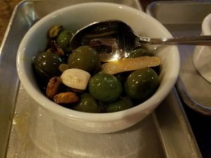 Warm Olives with rosemary, roasted garlic, pistachios and lemon infused olive oil. Delicious! at Donna Jean in San Diego