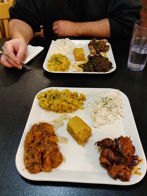 Front plate: BBQ plate with yams, mac and cheese, cornbread and rice. Back plate: Jerk chikin plate with collard greens, mac and cheese, cornbread and rice at Soul Good Vegan Cafe in Durham