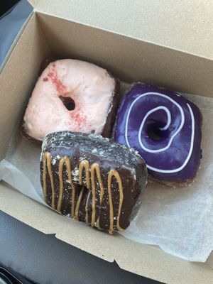 Clockwise from left: Strawberry Passionfruit, Ube, Twix  at Valkyrie Doughnuts in Orlando