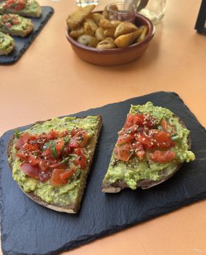 Avocado toast with tomato & seeds, & potato wedges.   at Roots in Tenerife
