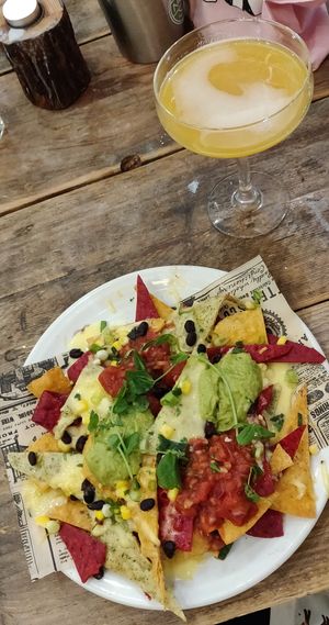 Plate of nachos with guacamole, salsa, and cheese. And a passion fruit cocktail.  at Natural Bar & Kitchen in Birmingham