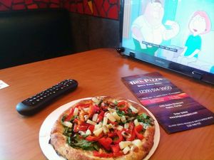 Eating a vegan "power pizza" while watching the tv in a booth. at BRK Pizza in Naples