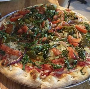 Red sauce, spinach, vegan mozzarella, Mancini fried peppers, red onion, garlic, tomatoes finished with garlic fennel vinaigrette, Gusto pizza spice, fresh basil. at Gusto Pizza in Des Moines