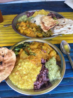 Medium plate in the front, large plate in the back, filled with various veggie dishes, dhal and rice at Dosha in Koh Phangan
