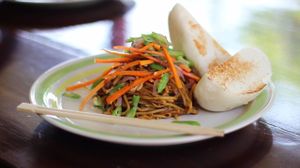 ASIAN INVASION. Egg noodles tossed in our asian style sauce with crushed peanuts and topped with sauteed vegetables. Served with a side of citrus, our homemade steamed asian-style bun, and chopsticks for a more asian feel ;) at Kurma in Camiguin