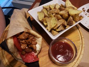 Vegan gyros served in a pita, with crispy potato wedges and spicy ketchup at Healthy Bites in Athens
