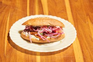 Sanduba de Calabresa: Sanduíche com nossa calabresa caseira na base de feijão carioca e vinagrete no nosso pão francês. Opcional com queijo). Aproximadamente 260g.  at Padoca Vegan in Sao Paulo