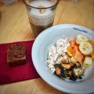 Soy latte, vegan chocolate cake, coconut milk musli, fruit salad, nuts and seeds at Zmorgeland in Basel