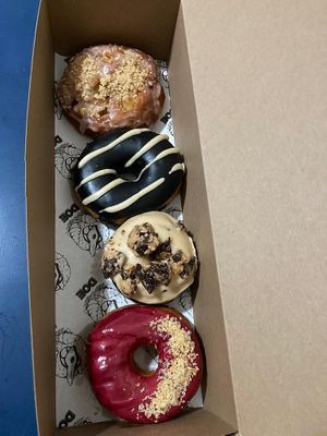 from top to bottom: bourbon apple fritter, black sesame, peanut butter cup, blackcurrant buttered toast at Doe Donuts in Portland