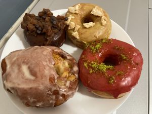 Clockwise from lower left: Pear caramel fritter, brownie pecan pie, golden milk and cookies, cranberry lime sugar at Doe Donuts in Portland