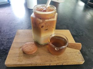 Iced latte with oatmilk, served with a ginger biscuit. at Rainbow Cafe in Ella