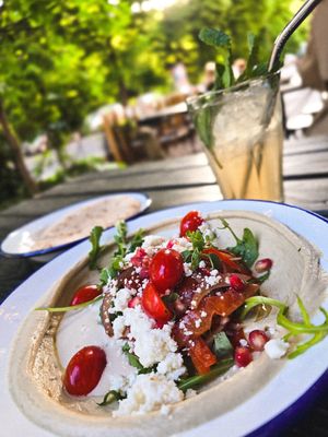 HUMMUS DER WOCHE: mit Tomaten-Paprika-Rucola-Salat in fruchtigem Granatapfeldressing, Tahini-Sauce, frischen Granatapfelkernen, Feta und Oregano at Mashery - Hummus Kitchen in Cologne