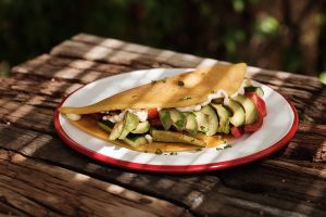 Eggless omelette! Gram-flour-based omelette folded with spinach over pan-sautéed mushrooms  and semi dried tomatoes, cashew cream cheese, sour cream with avocado and salsa!  at Seva Table in Dubai