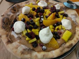 Pizza dulce con crema de chocolate y avellanas, frutas y nata vegana  at Pizzi & Dixie in Madrid