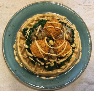 Fa-waffle: Gluten-free waffle topped with maple-cumin kale, caramelized onions, sweet potato falafels and sun-dried tomato cashew cream at Surya Cafe in Fitchburg