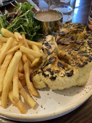 The Cajun cauliflower steak with satay sauce, rocket salad, and fries.  at Bitter & Twisted in Chipping Norton