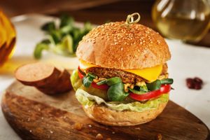 Mr. Vegan "Cheeseburger" - A fluffy sourdough bun with a Mushroom-Walnut-Chickpeas-Red Beans - Patty, pickles, tomatoes, two home made sauces (tahini&mayo), finished with a slice of coconut "cheddar cheese" at Sara Green - Vegan Bistro in Bucharest