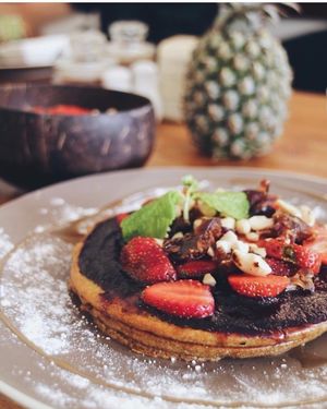 Blueberry or Matcha Vegan Pancakes, topped with nuts and strawberries.  at Cafe Organic in Canggu