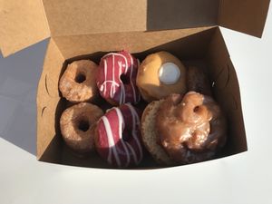 Lots of beautiful donuts like raspberry glazed, orange creamsicle, birthday cake, cronut, apple fritter, and toasted coconut. at Fry Baby Donuts in Buffalo