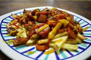 Picada mixta de chorizo, chicharron y salchicha suiza sobre una cama de papas a la francesa. Nuestros alimentos son 100% Veganos y las carnes vegetales que usamos para esto son elaboradas a partir de la soya. at Mar y Hojas Cocina Vegana in Cartagena