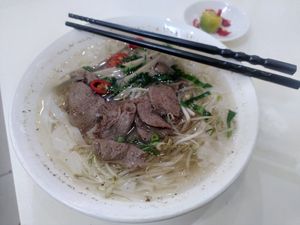 Big bowl of phở with mock beef, rice noodles and veggies. Lime and chili on the side. at Loving Hut - Ba Dinh in Hanoi