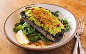 Smashed avocado and artisan charcoal bread in a bed of fresh leaves  at Miranda Cafe in North London
